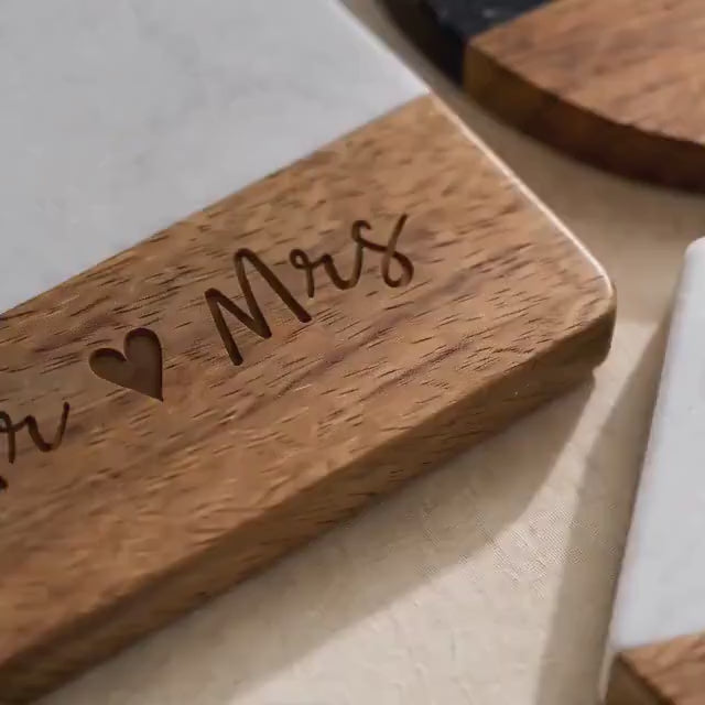 Personalized marble and wood coasters engraved with a family name, shown as a set of four